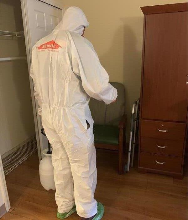 A SERVPRO employee in a room with a hazmat suit on.