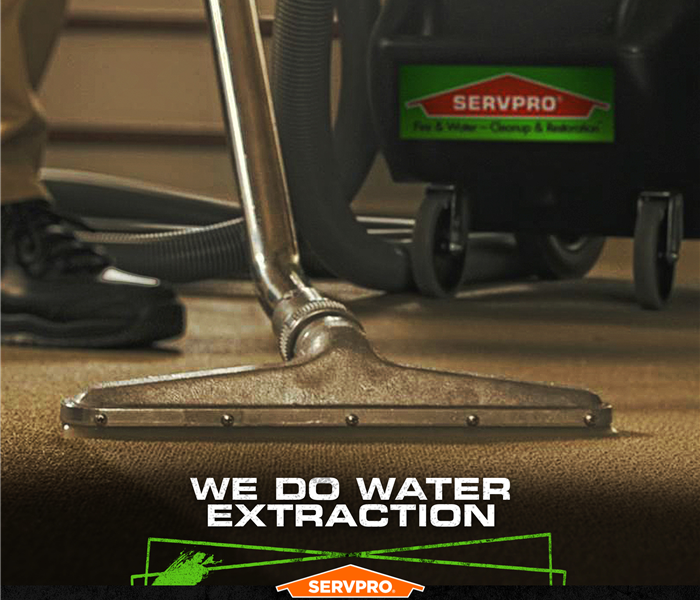 SERVPRO tech extracting water from hardwood floors with the caption: CALL IN THE CLEANUP TEAM