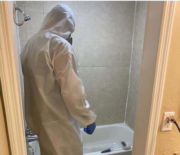 SERVPRO employee in PPE in a mold damaged bathroom