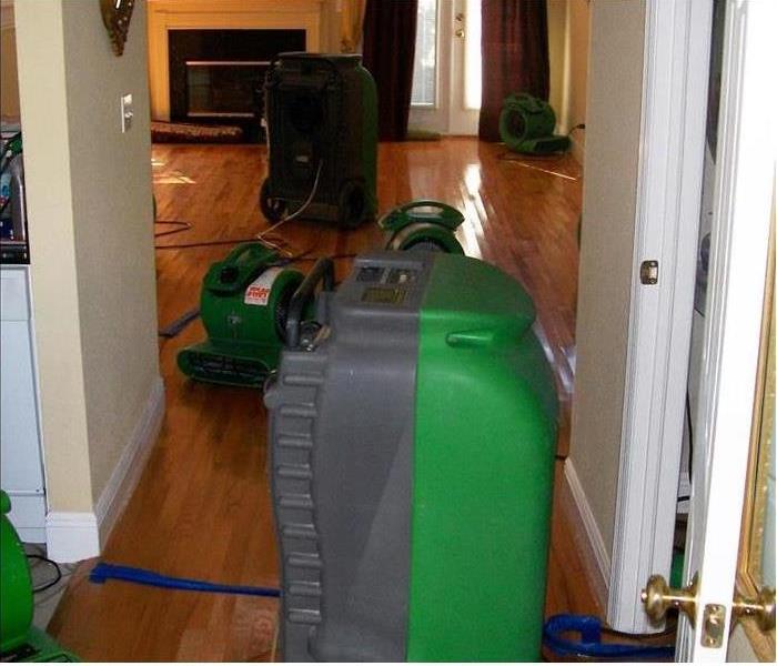 large industrial-grade dehumidifiers and air movers removing moisture from hardwood floors